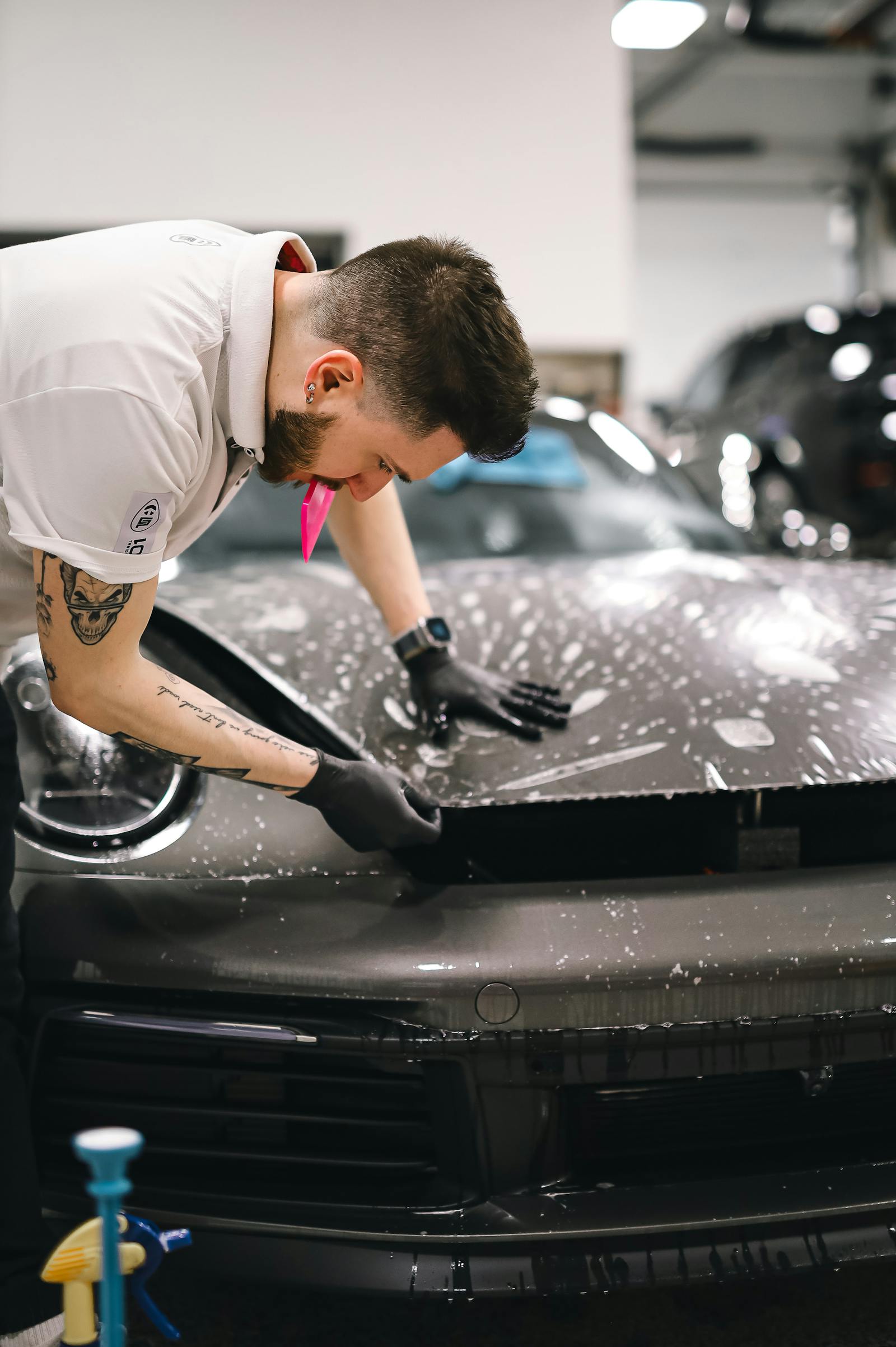 Installer applying paint protection film to a vehicle hood